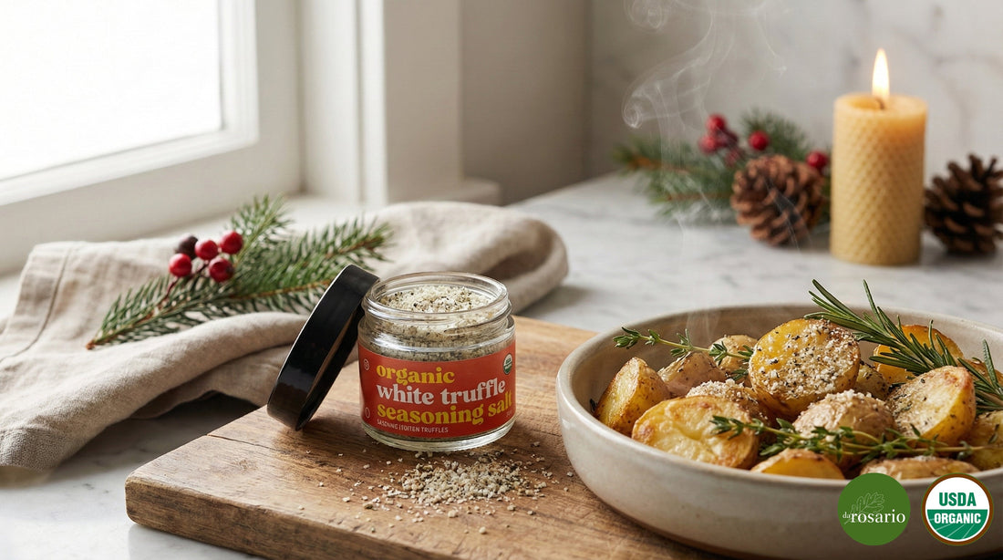 A jar of daRosario Organic White Truffle Seasoning Salt on a rustic wooden board next to a bowl of steaming roasted potatoes with rosemary, styled in a warm Christmas kitchen setting with pine branches and soft candlelight.