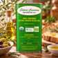 A green canister of Silveri Cesarino 100% Organic Extra Virgin Olive Oil stands on a rustic wooden table, surrounded by olive branches, a glass bottle of oil, olives, and sliced bread.