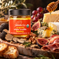 A jar of daRosario Organic White Truffle Honey on a charcuterie board with figs, brie, prosciutto, almonds, walnuts and grapes