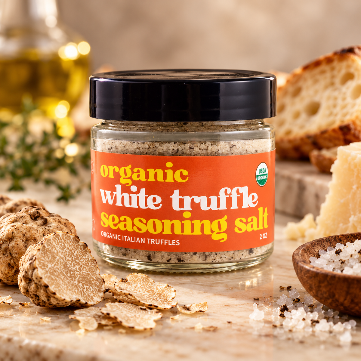 A jar of daRosario organic white truffle seasoning salt on a marble surface with sliced truffles, bread, cheese and a bottle of oil
